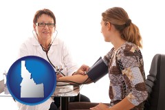 idaho map icon and a female nurse practitioner checking a patient's blood pressure