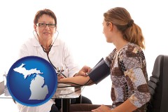 michigan map icon and a female nurse practitioner checking a patient's blood pressure