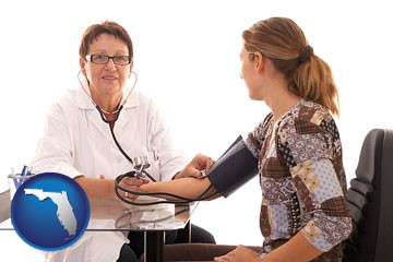 a female nurse practitioner checking a patient's blood pressure - with Florida icon