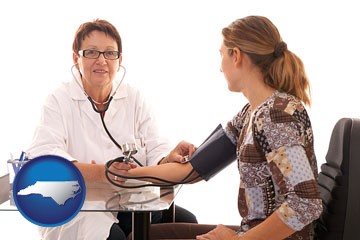 a female nurse practitioner checking a patient's blood pressure - with North Carolina icon