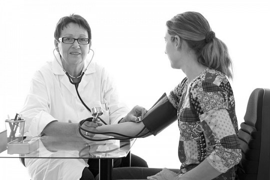 a female nurse practitioner checking a patient's blood pressure